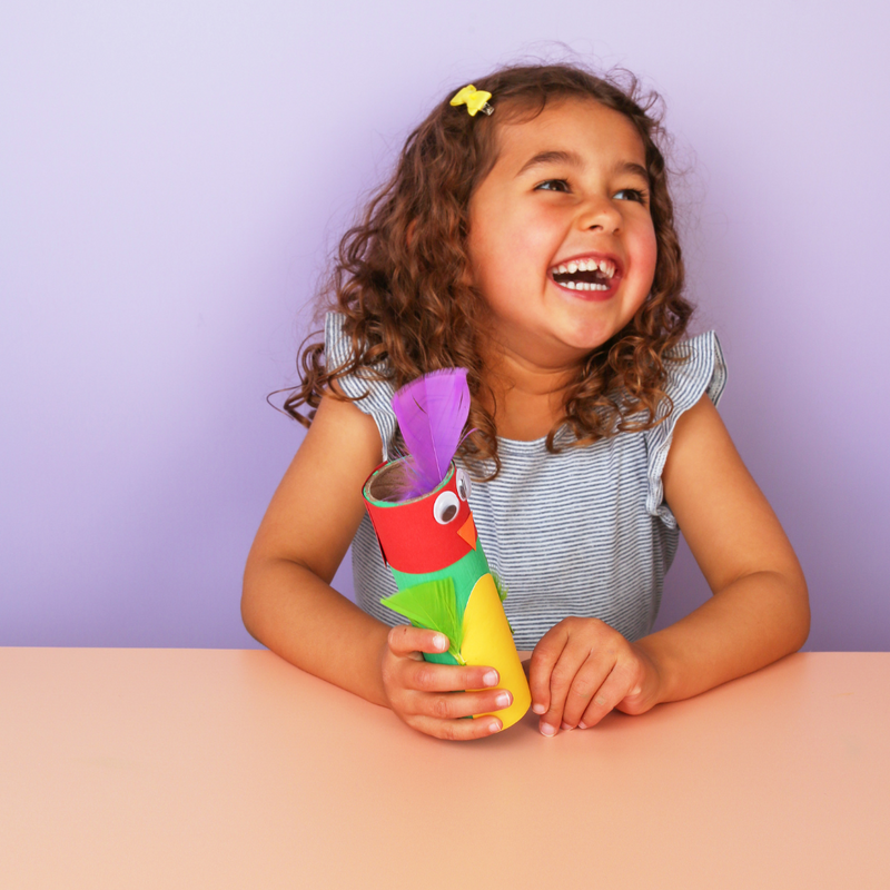 Child holding a colorful toy with a purple top against a light purple background