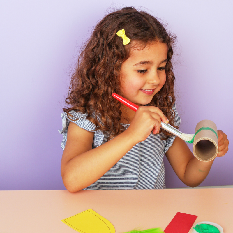 Child playing with a colourful craft on a purple background