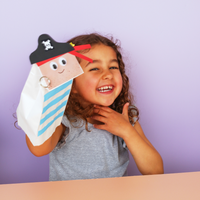 Child holding a hand crafted pirate puppet against a purple background