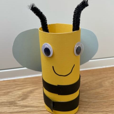 Cardboard tube bee craft made from a loo roll with paper wings and pipe cleaner antennae