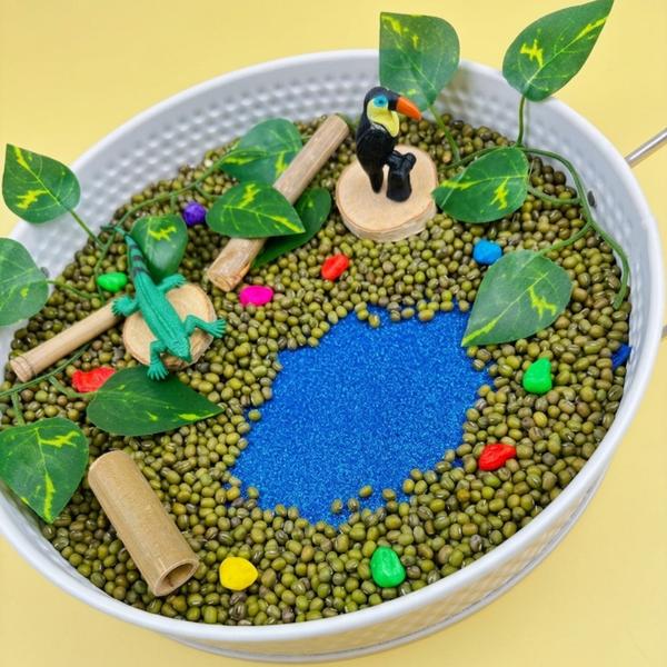 Jungle sensory tray: green lentils with a blue rice pool, cork logs, leaves and jungle animals