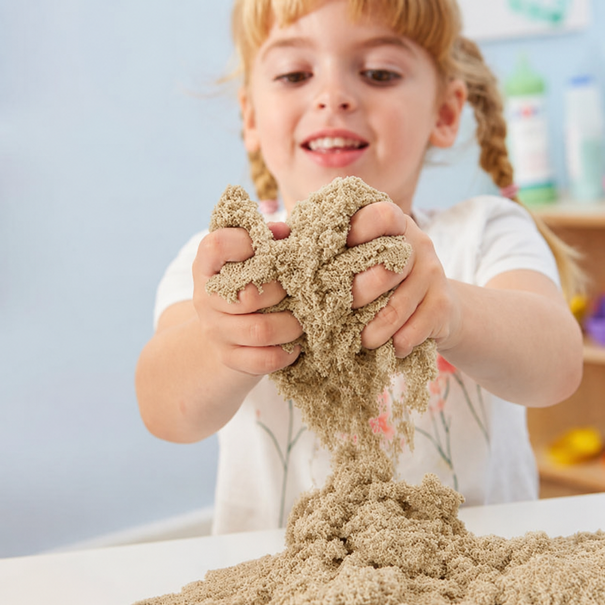 Child squeezing a handful of kinetic sensory sand