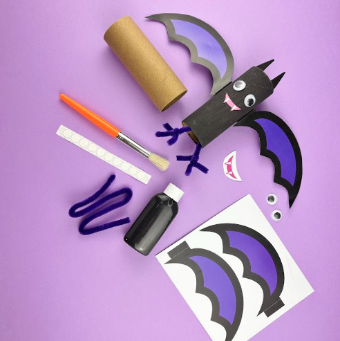 Wicked winged bat craft: a cardboard tube painted black with purple wings, googly eyes and fangs, shown with the black paint, brush, pipe cleaners and printed wing templates