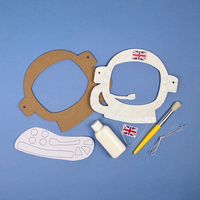 Craft materials including cardboard cutouts, paint, brush, and flags on a blue background to make an astronaut mask