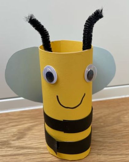 Finished loo roll bee craft with googly eyes, black stripes and white paper wings