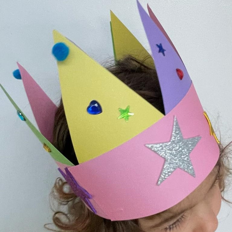 Paper crown craft decorated with coloured triangles, gems and pom-poms