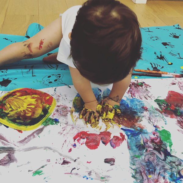 Toddler crafting at a table with paint and paper