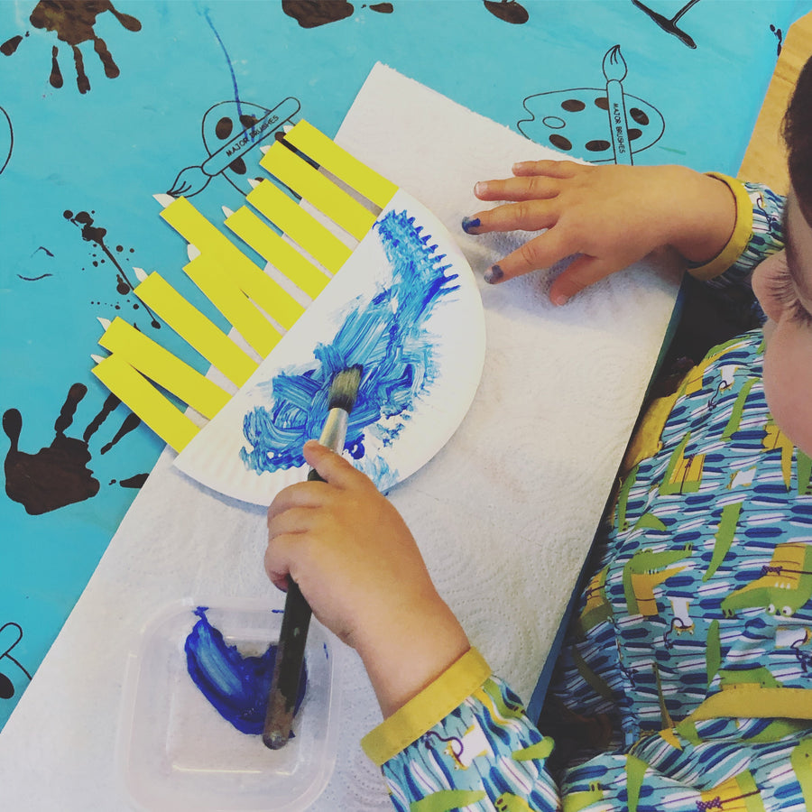 Paper plate menorah craft with nine paper candles and a ribbon to hang it