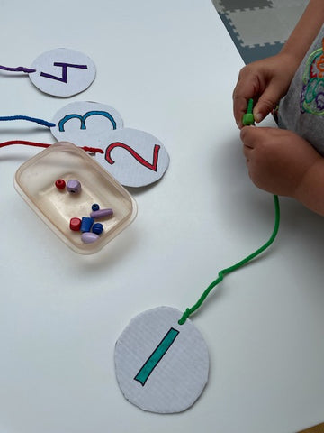 Numbered cardboard circles with pipe cleaners threaded with beads