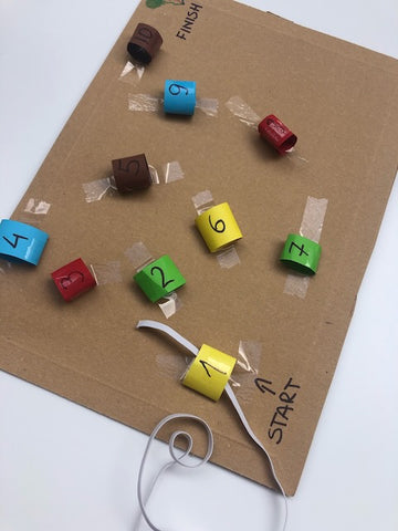 Numbered paper loops taped to cardboard with string threaded through in order