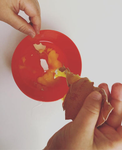 Toddler cracking an egg into a bowl of pancake batter