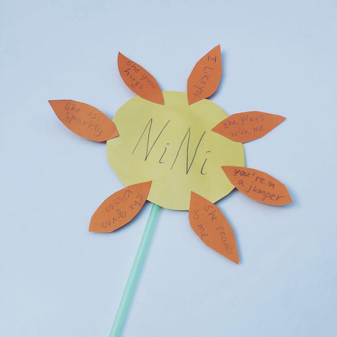 Paper flower on a straw with yellow petals, each labelled with a reason someone is special